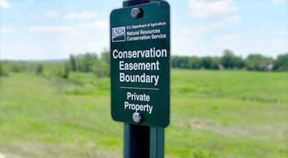 A green USDA sign marks the boundary of a conservation easement and designates the land as private property.
